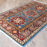 A traditional Persian-style area rug with a blue field, red and beige medallions, and a patterned border, shown on a light wood floor.