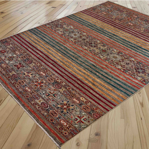 A rectangular Afghan Loribaft rug with a traditional geometric pattern and plain modern stripes in red, green, gold, and orange tones, shown laid out on a light wood plank floor.