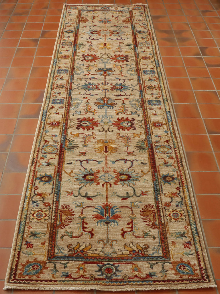 A beautiful runner with a mottled beige background and simple floral design. The ground colour is lovely and light and acts as a good foil to the other colours which include rust, green, cream, yellow, old gold, light and dark blue with touches of a deep red accent colour.  The floral design covers the entirety of this piece.  Larger floral depictions in the main section, smaller ones in the border. 