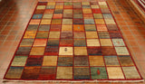 A gridded pattern across the entirety of this rug broken up by bands of warm red.  Each box in the grid has a blend of colours that flow into each other. These colours consist of autumnal reds, blues, greens, golden yellows and creams.  There are a few randomly positioned depictions placed in some of the boxes.  