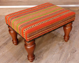 Theses Turkish Kilim stools often uses salvaged pieces.  This use produces an interesting look with the pattern being offset rather than centred, making the pieces unique and different. On this occasion the stool has a stripy design going across the length of the stool.  The bands vary in width.  The colour palette used is striking with lime green, bright orange, deep red. black and cream. 