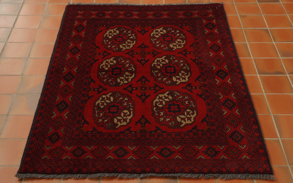 Six medallions laid out in a symmetrical pattern across the main part of this rug using deep blue and an oatmeal shade can be seen.  There are a number of borders of varying widths with geometric designs upon them, again using the deep blue on a strong red ground.  Shots of orange/yellow are used to highlight aspects of the design. 