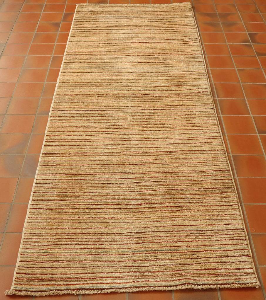 A soft oatmeal gabbeh runner with subtle bands of colour across it.  These being in terracotta. green and golden yellow predominantly. 