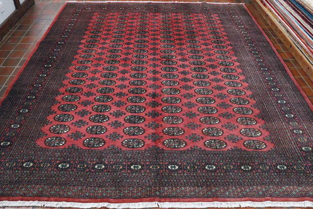 A rose red base colour with symmetrically laid out motifs laid out in a 6 x 21  grid formation.  The decoration being stylized flowers using peach, soft green and cream as the colours, edged in black.  There are a complex series of borders, creating a wide framework.  These are of differing widths. 