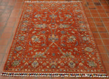 A burnt orange ground with classic design using bright shades of green, blue, purple, cream, and golden yellow.  The toggle ends are bright colours to contrast.  
