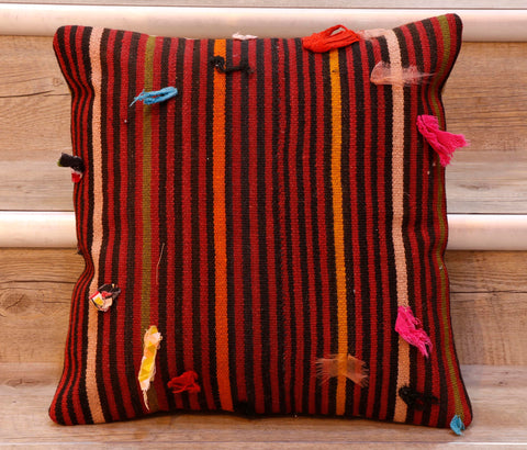 The pieces are often salvaged from old kilim so the pattern or Motifs may be cut in unusual and interesting ways.   This cushion has bands of red, black, orange, peach, green and yellow. There are multiple coloured wish knots upon it in bright colours. 