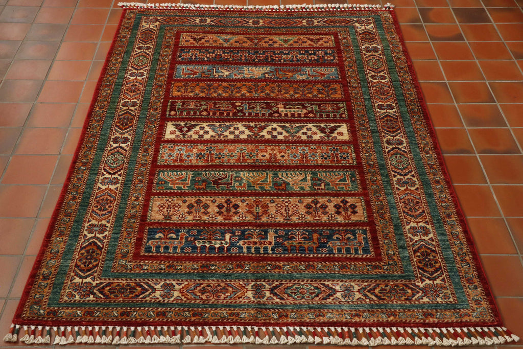 This piece has bands of colour, these being dark blue, peach, sea green, rust, cream and deep red.  Upon which can be found depictions of birds and animals.  There are a series of borders using the same colour palette some plain, others coloured with geometric designs on them.  The ends of this rug have toggles of colour, the same of which are used in the rug. 