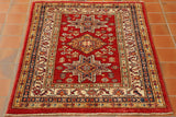 Bright red central ground with three decorative motifs in the centre.  Series of borders around the central section. Colour palette using golden yellow, blue, cream and green.  