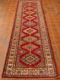 Bright red central ground with a series of medallions through nthe length.  Border in cream with narrower borders on either side.  Colours used in the decoration consist of dark blue, green, golden yellow, peach and cream. 
