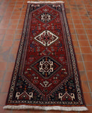 Warm red background through the central area with three large medallions upon it.  The middle one cream in color, the other two the deepest of blues.  All are highly decorated with stylized flowers, birds and butterflies.  There are triangular sections in each corner also decorated.   There is also border made up using the cream and deep blue.  The decoration is executed using various reds, greens, yellows and oranges.    